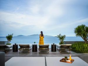 una mujer con un vestido amarillo parada en una terraza con vistas al océano en Hoiana Hotel & Suites, en Hoi An