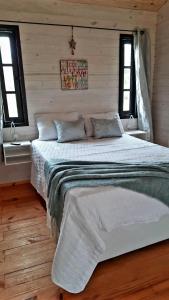 a bedroom with a white bed with two windows at Ocean Paradise 2 in Punta Del Diablo