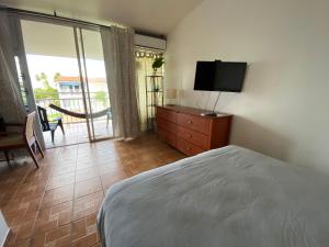 um quarto com uma cama, uma televisão e uma varanda em Paradigm Villa Dorado em Dorado