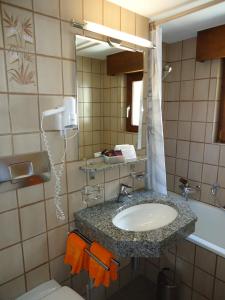 ein Badezimmer mit einem Waschbecken, einem WC und einem Spiegel in der Unterkunft Hotel Monte-Moro in Saas-Almagell