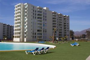a large apartment building with chairs and a swimming pool at Departamento en Papudo Laguna in Papudo