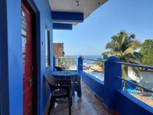 a blue house with a table and chairs on a balcony at Red Rock Arambol Beach in Arambol