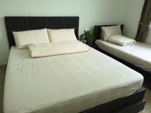 una camera da letto con due letti con lenzuola bianche di Tangkak Greenville Homestay a Tangkak