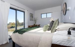 Tasman View Accommodation في Lower Moutere: غرفة نوم بسرير كبير ونافذة كبيرة