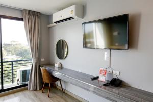 Habitación con escritorio, TV y ventana. en Le Lert Hotel Ratchaburi en Ratchaburi