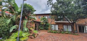 a brick building with trees and a brick driveway at Aero Lodge Guest House in Middelburg