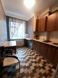 una cucina con pavimento a scacchi, tavolo e sedie di Большая Перспективная 46 a Kropyvnyc'kyj