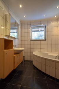 a bathroom with two sinks and a tub and a mirror at MAXAlpin Appartements in Längenfeld