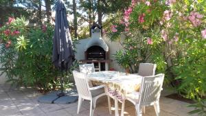 een tafel en stoelen met een parasol en een open haard bij Maison ronde atypique et unique in Torreilles