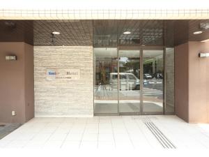 une entrée à un bâtiment avec un panneau sur celui-ci dans l'établissement Smile Hotel Okinawa Naha (Tomari Port), à Naha