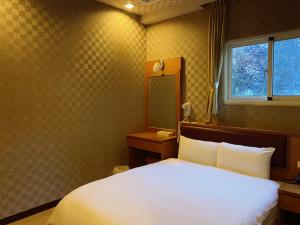 een slaapkamer met een wit bed en een raam bij 自在旅墅山莊 in Guoxing