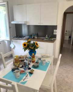 una cocina con una mesa blanca con un jarrón de girasoles en B&B MimmoSole, en Agropoli