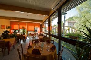 - un restaurant avec des tables, des chaises et de grandes fenêtres dans l'établissement Logis Hotel Restaurant Auberge Les Rives de l'Arzon, à Vorey