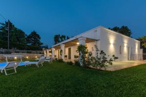 a white building with chairs in a yard at night at Casale Ramunno in Ostuni