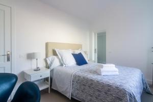 a bedroom with a bed with blue pillows and a chair at Rooms & Suites Princesa Mercedes in Puerto del Carmen