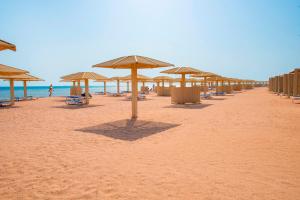 a beach with umbrellas and chairs and the ocean at Premier Le Reve Hotel & Spa Sahl Hasheesh - Adults Only 16 Years Plus in Hurghada
