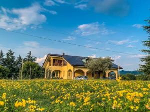 una casa amarilla en un campo de flores en B&B Alla Roggetta, en Cremella