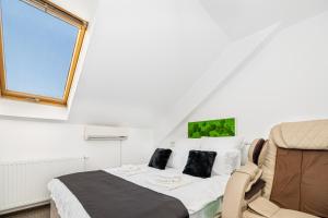 a bedroom with a bed and a chair and a window at Bada Bing Residence in Braşov