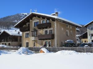 un edificio en la nieve con una valla en Bait da Salient MyHoliday Livigno, en Livigno