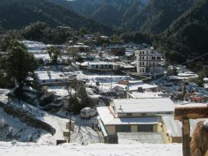 a town covered in snow with mountains in the background at Janardan Resort Pangot Nainital in Nainital