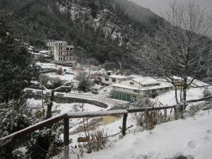 a town in the snow with houses and a mountain at Janardan Resort Pangot Nainital in Nainital