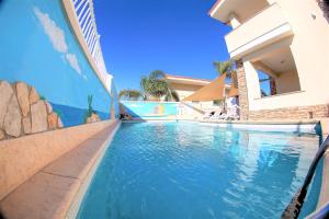 uma piscina ao lado de um edifício com água azul em Villa Paglianiti - Your FAMILY Residence! em Briatico