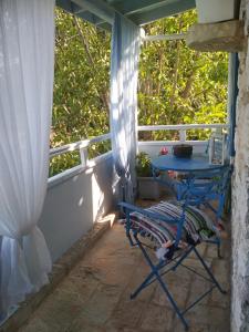 une table bleue et une chaise sur une terrasse couverte avec une fenêtre dans l'établissement Petrinο Katochori, à Katokhórion