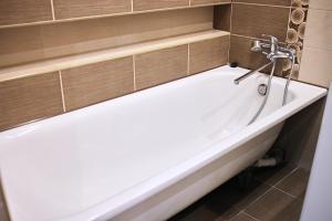 La salle de bains est pourvue d'une baignoire avec un robinet. dans l'établissement Babylon Apartments On Soborna, à Rivne