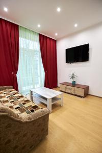 Il comprend un salon doté d'un canapé et d'une télévision à écran plat. dans l'établissement Babylon Apartments On Soborna, à Rivne