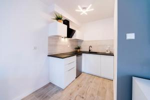 uma cozinha com armários brancos e uma bancada em Apartamenty EverySky - Leśny Dom 16 - 18 em Karpacz