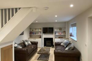 a living room with two leather couches and a staircase at Bagpuss Cottage Stunning 2 bedroom cosy cottage in Witney