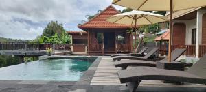a pool with chairs and umbrellas next to a house at Nadya Homestay in Munduk