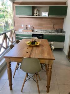 a wooden table in a kitchen with a bowl of fruit on it at Lindo apartamento Riverside Imbassaí in Imbassai