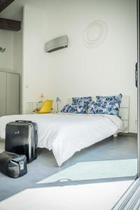 1 dormitorio con 1 cama y 1 maleta en el suelo en Sous les oliviers - Piscine chauffée à débordement- Studios climatisés, en Saint-Maximin-la-Sainte-Baume