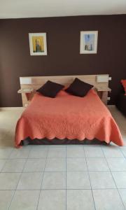 a bedroom with a bed with an orange blanket and pillows at La Doucinière 