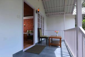 a room with a table and a chair on a porch at Rainforest Munnar in Munnar
