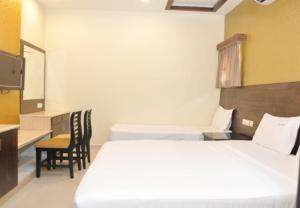 a hotel room with two beds and a desk at Hotel Grand Parkway in Tambaram