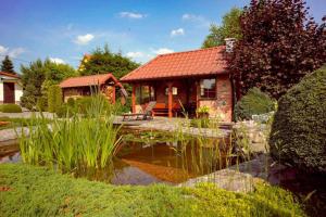 a small house with a pond in front of it at Apartament na Mazurach in Ostróda