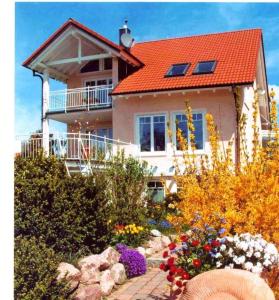 uma casa com um telhado vermelho e algumas flores em ferien-domizil-schneider em Uhldingen-Mühlhofen