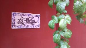 a sign on a red wall with a plant at S'Attobiu B&B And Guest-Houses in Teulada