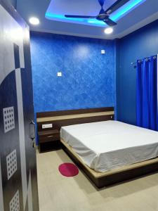 1 dormitorio con 1 cama con pared azul en VISWAMURTI RESORTS en Chālsa Mahābāri