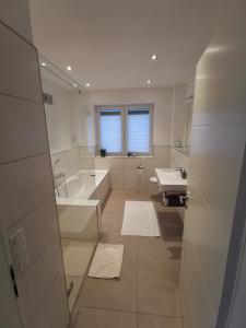 een witte badkamer met een bad en een wastafel bij Ferienwohnung Oldenburg Bloherfelde in Oldenburg