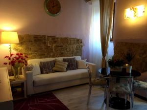 a living room with a white couch and a clock on the wall at Appartamento Casa del Colle in Colle di Val d'Elsa