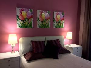 1 dormitorio con 3 pinturas de flores en la pared en Appartamento Casa del Colle, en Colle Val D'Elsa