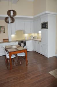 uma cozinha com armários brancos e uma mesa e cadeiras de madeira em M2-Apartment em Szombathely