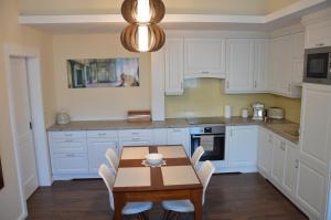 uma cozinha com uma mesa de madeira e armários brancos em M2-Apartment em Szombathely
