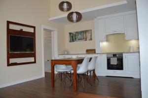 a kitchen with a wooden table and white chairs at M2-Apartment in Szombathely