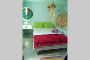 1 dormitorio con 1 cama con almohadas verdes y rojas en Traditional house Utopia Makri Gialos, en Pévkoi