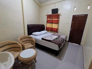 a small bedroom with a bed and two chairs at WELCOME TO WISMA SUNRISE GUEST HOUSE 10 minutes by walking to the big fruit market in Berastagi