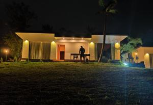 a man standing in front of a house at night at Peakaavu Cottages in Idukki